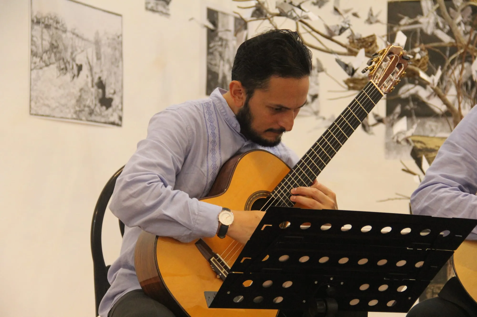 Guitarrista del Cuarteto de México concentrado en su partitura durante el concierto.